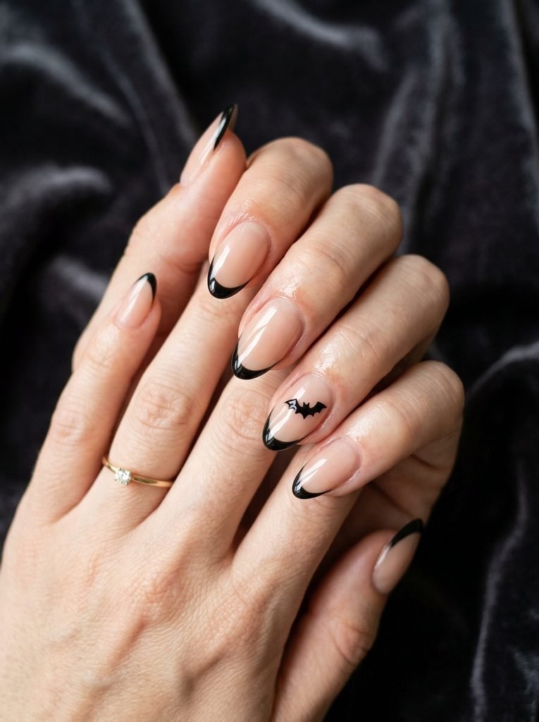Minimalist glossy black French tip nails with tiny bat nail art on nude base - spooky but classy Halloween nails"